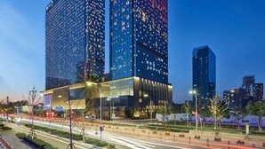 A modern hotel with two prominent towers, featuring a glass facade and illuminated signage. - Hilton Beijing Tongzhou (Tongzhou)
