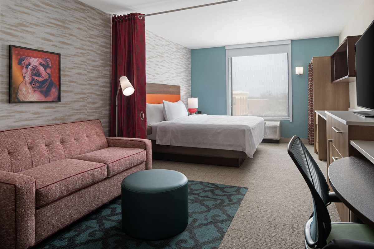 Ein Hotelzimmer mit Bett, Sofa, Schreibtisch und Fernseher.