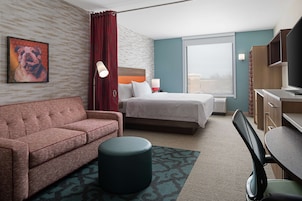 A hotel room with a bed, a sofa, a desk, and a television.