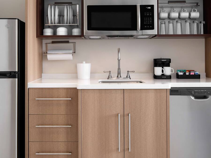 Een moderne keuken met roestvrijstalen apparatuur, houten kastjes en een koffiezetapparaat.