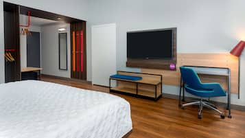 Una habitación de hotel moderna con una cama grande, un escritorio con silla, un televisor de pantalla plana y una lámpara roja.