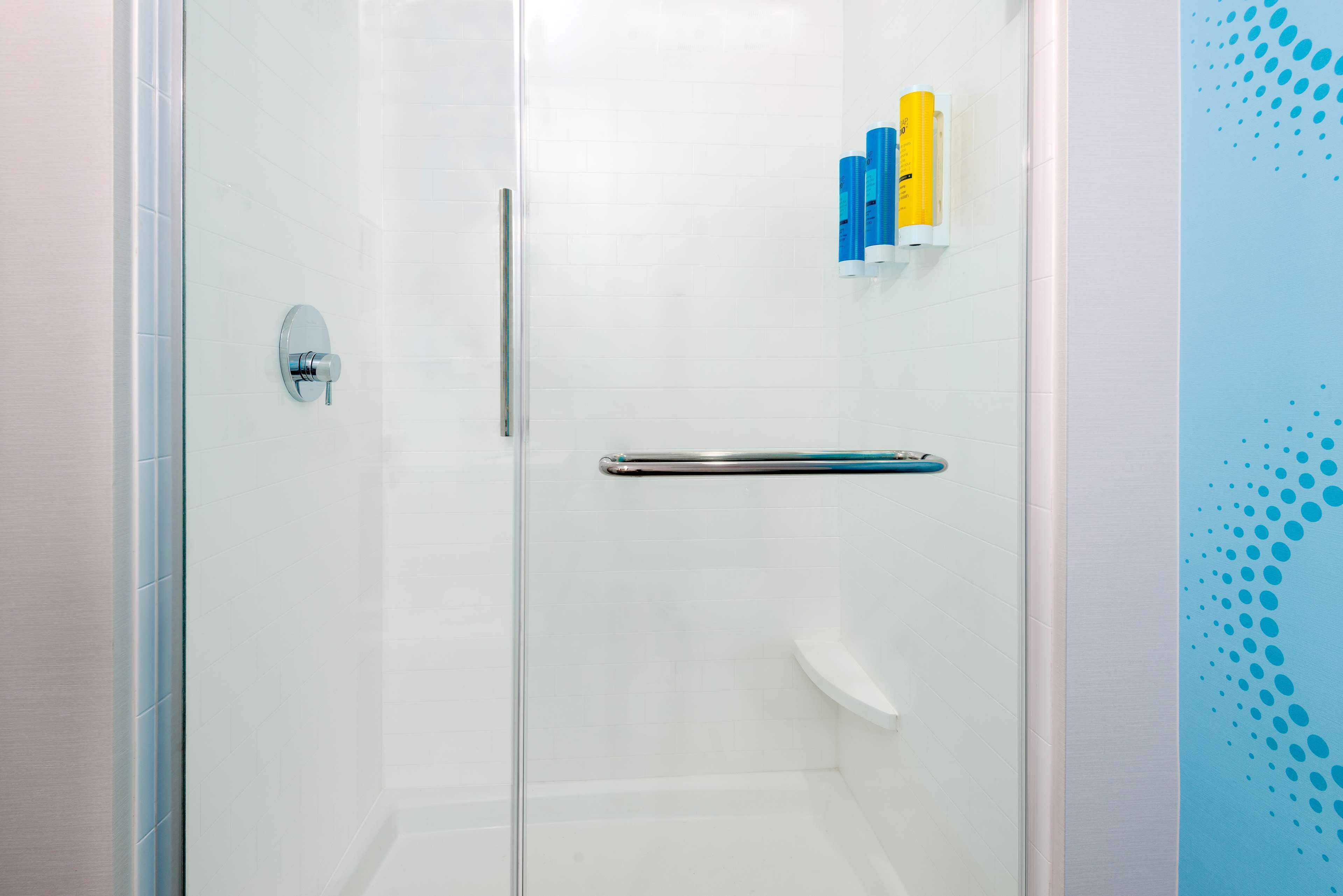 A glass-enclosed shower with a metal handle and a white towel rack.
