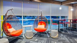 A modern interior with hanging chairs, tables, and a view of the parking lot. - Tru by Hilton Spartanburg (Spartanburg)