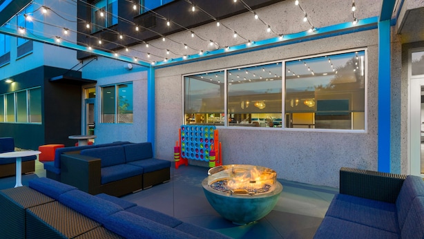 An outdoor seating area with sofas, a fire pit, and string lights. - Tru by Hilton Spartanburg (Spartanburg)