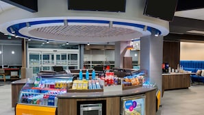 A self-service kiosk with a variety of snacks and beverages, a microwave, and a refrigerated display. - Tru by Hilton Spartanburg (Spartanburg)