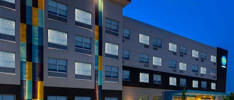 A modern hotel with a multi-story structure, large windows, and a prominent vertical light strip.