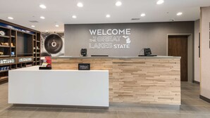 A reception desk with a "Welcome to the Great Lakes State" sign, a clock, and a "Hilton Honors" sign.
