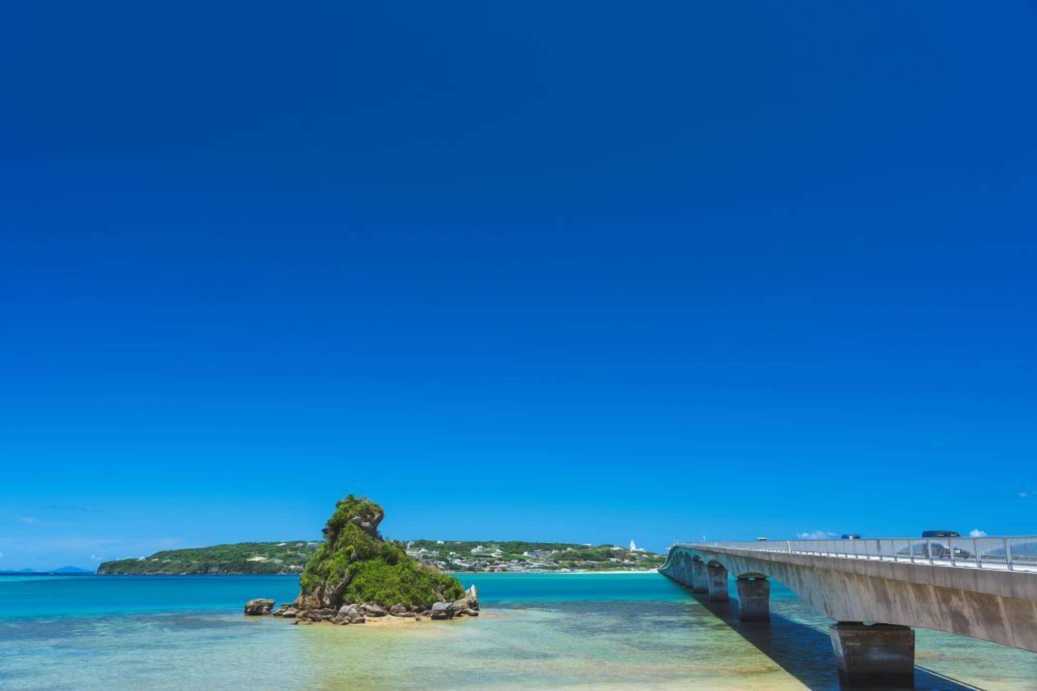 A coastal bridge with clear blue waters and a small island with greenery.