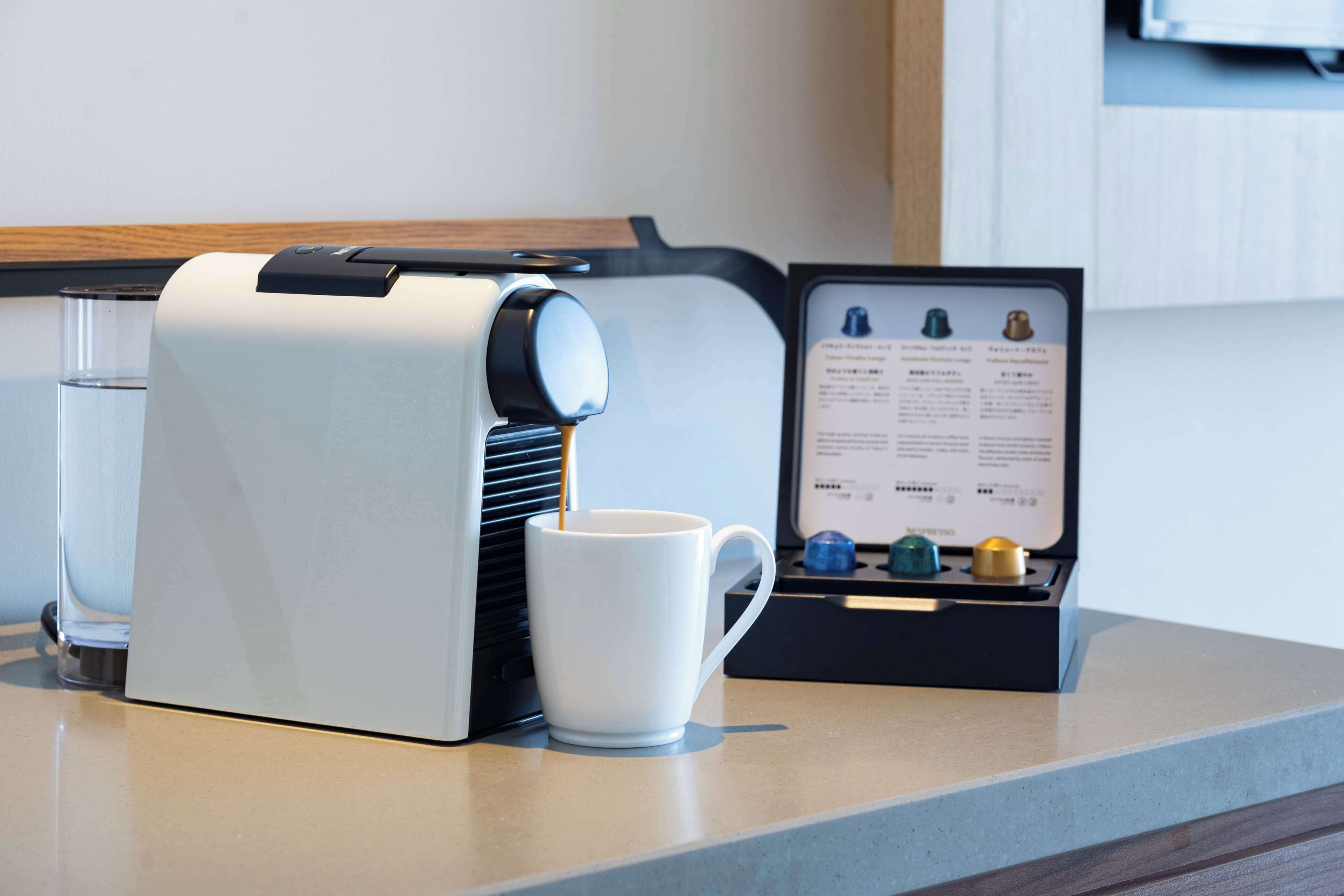 A coffee machine with a menu display and a white mug on a countertop.