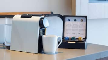 A coffee machine with a menu display and a white mug on a countertop.