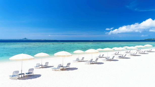 A beach with white umbrellas and lounge chairs. - Hilton Okinawa Sesoko Resort (Motobu)