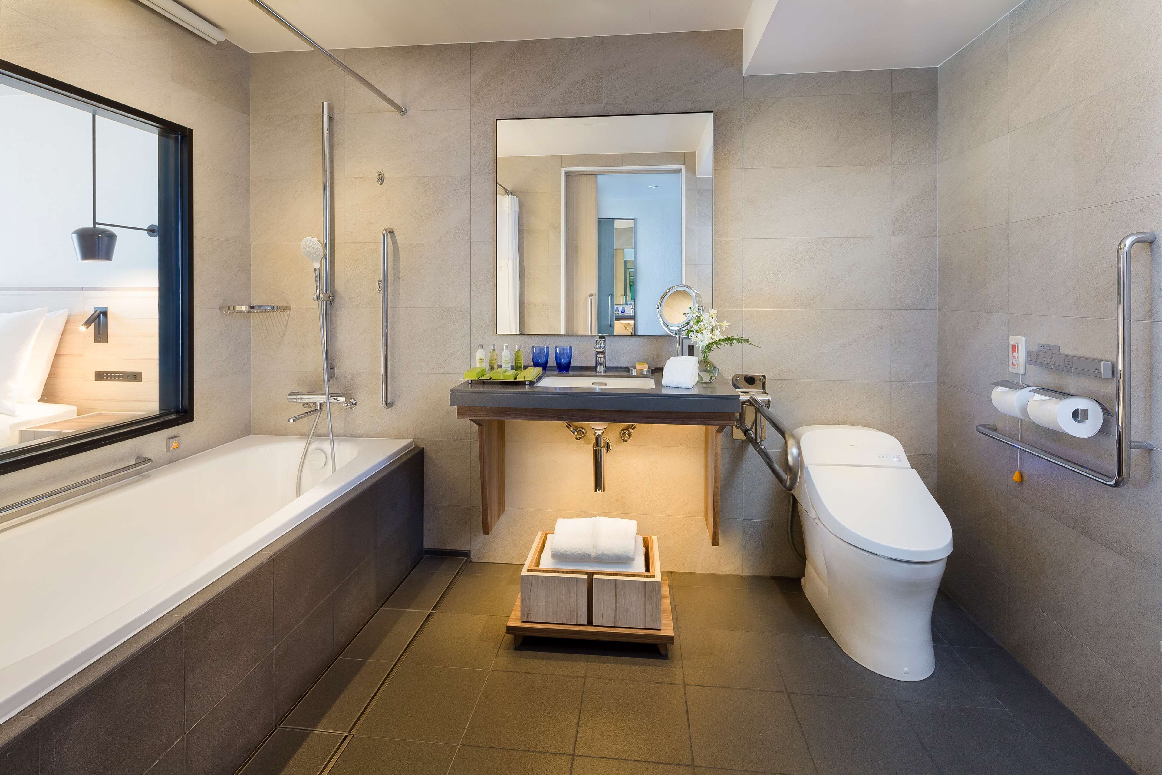Un baño moderno con bañera, lavabo con espejo, inodoro y ducha.