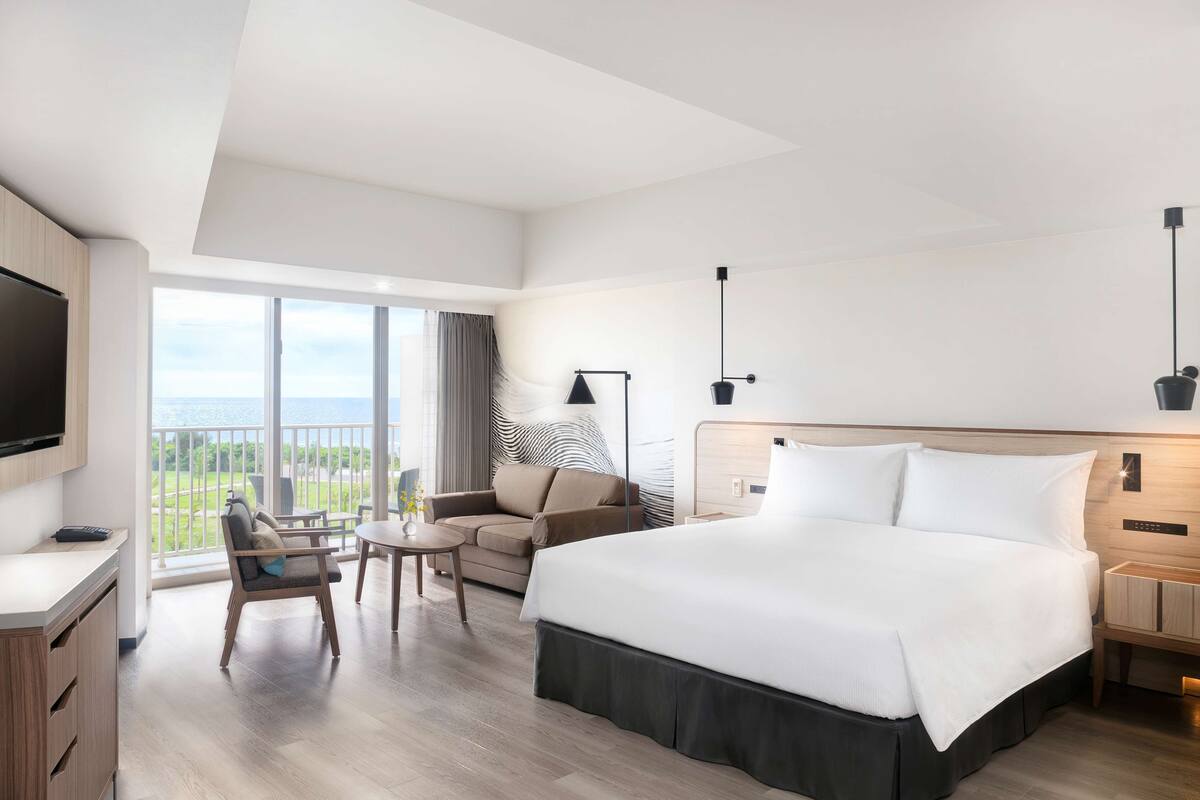 Una habitación de hotel moderna con una cama grande, un escritorio, una silla y un televisor.