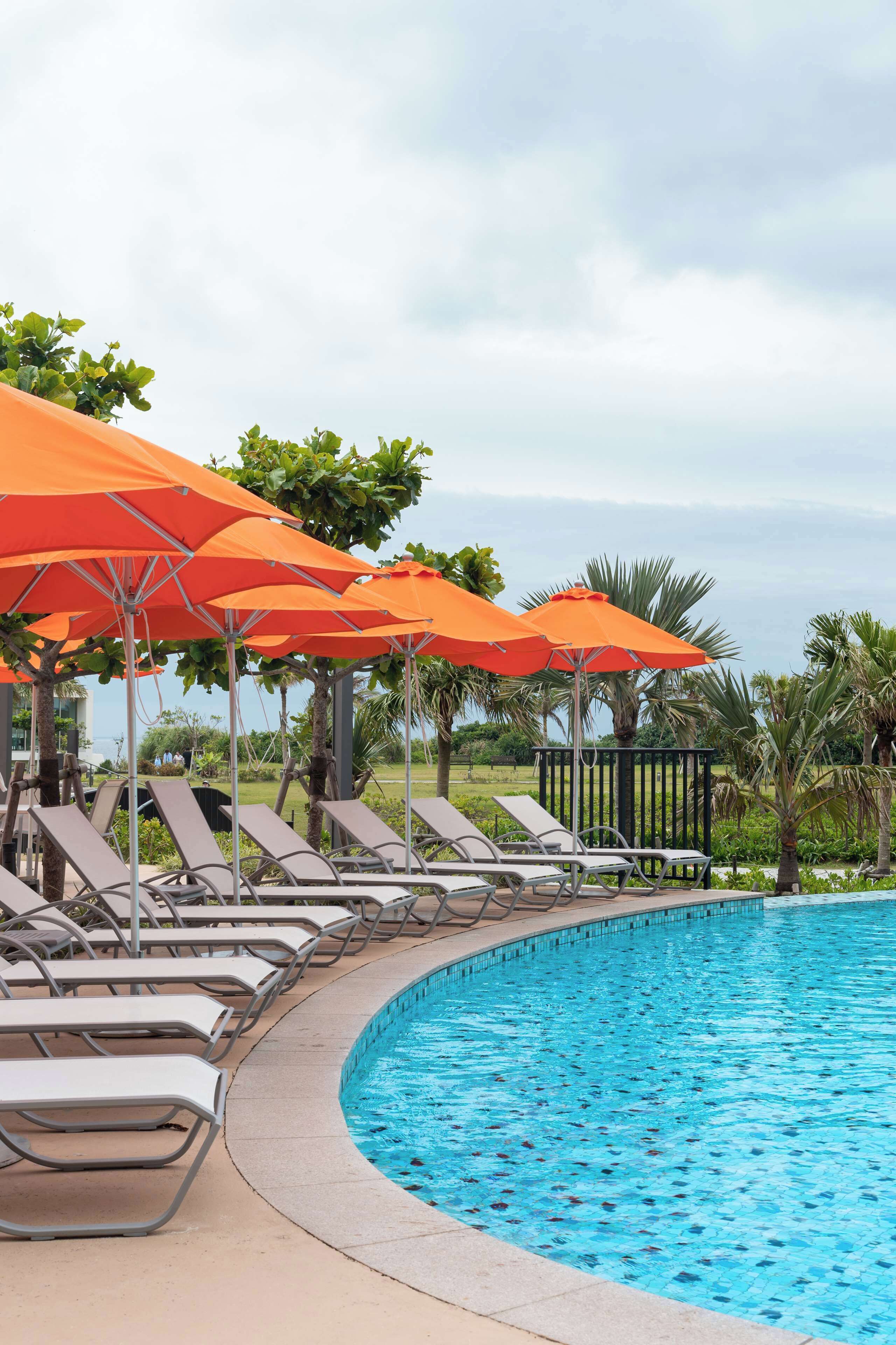 A swimming pool with lounge chairs and orange umbrellas.