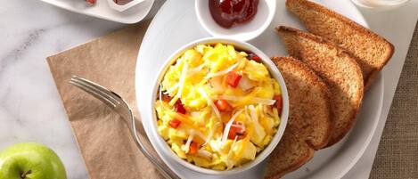 A breakfast plate with scrambled eggs, toast, jam, and butter.