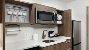 A modern kitchen with a built-in microwave, stainless steel sink, and a dishwasher. - Home2 Suites by Hilton Stuart (Stuart)