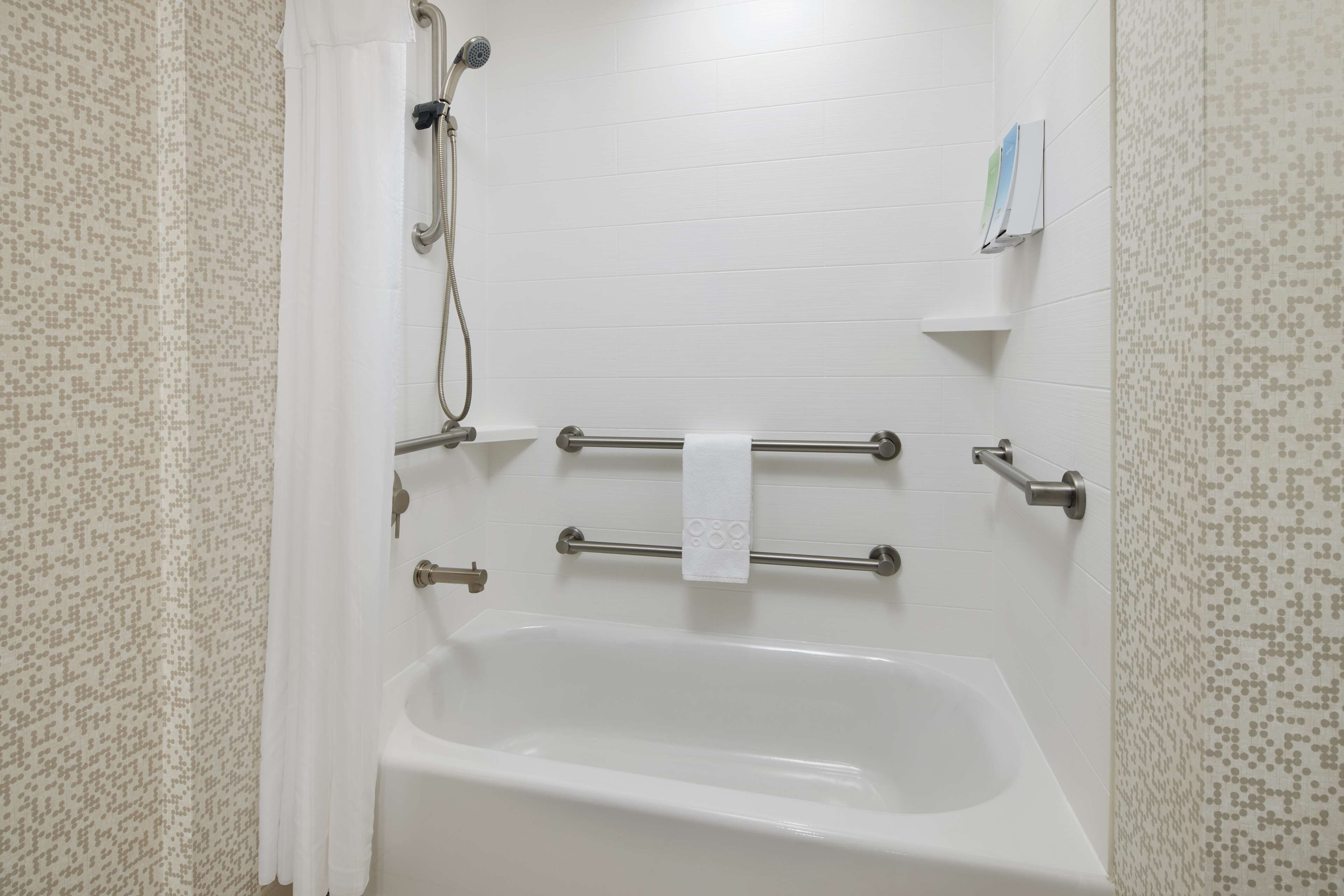 Une salle de bain avec une baignoire blanche, une pomme de douche et un porte-serviettes.