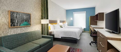 Una habitación de hotel con un sofá verde, dos camas, un televisor y un escritorio.