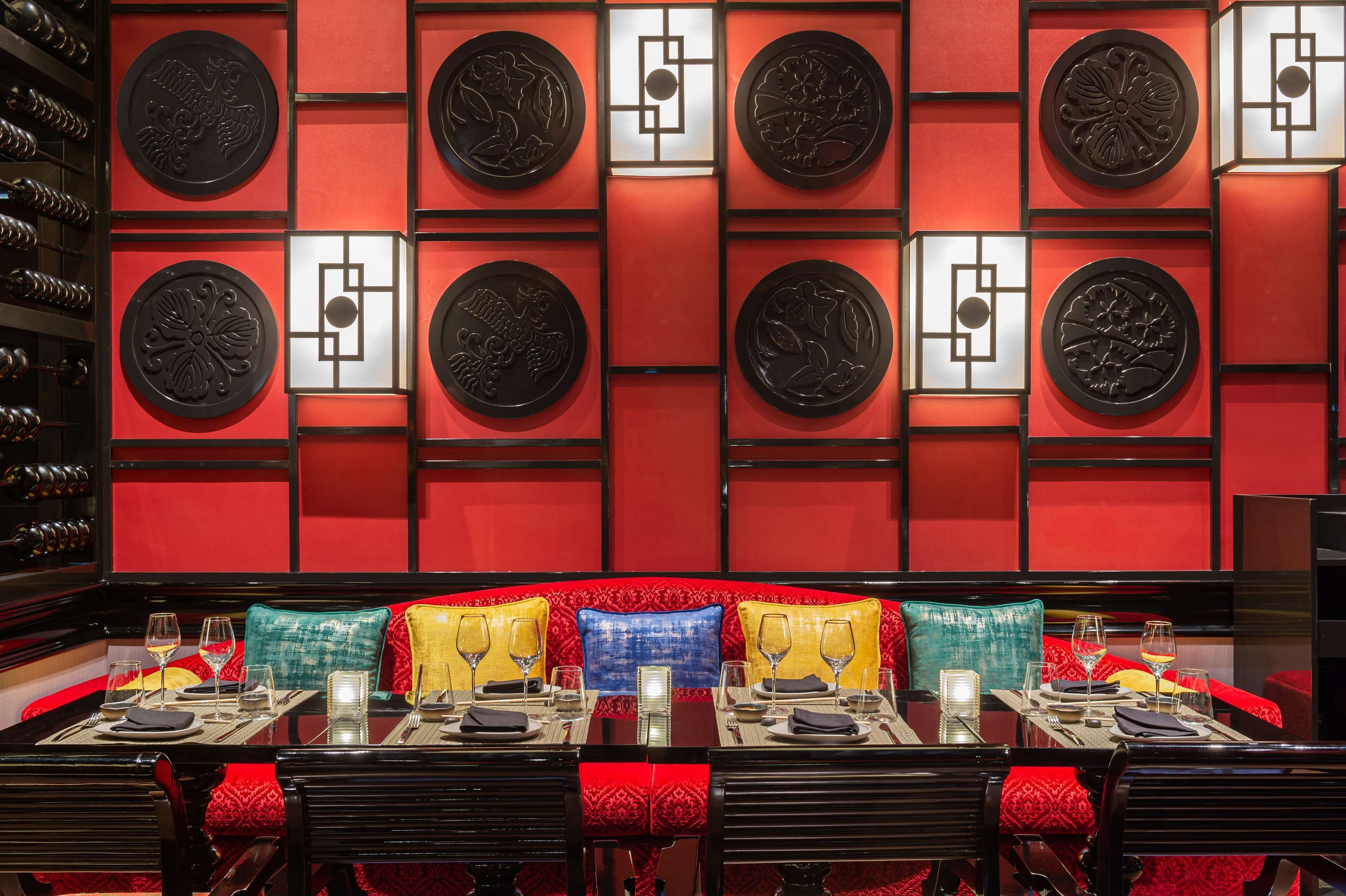 A restaurant with red walls, black and white decorative panels, and red upholstered seating.