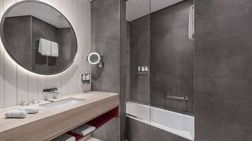 A modern bathroom with a large mirror, a sink, a shower, and a bathtub.