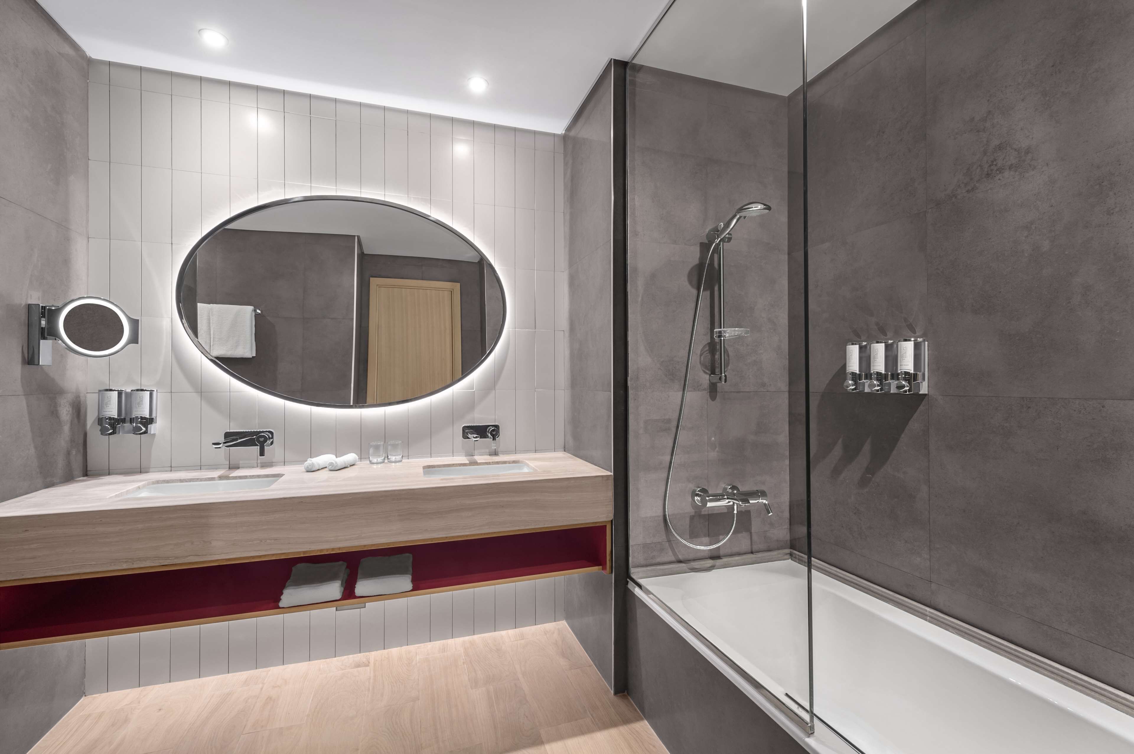 A modern bathroom with a large mirror, a bathtub, and a shower.