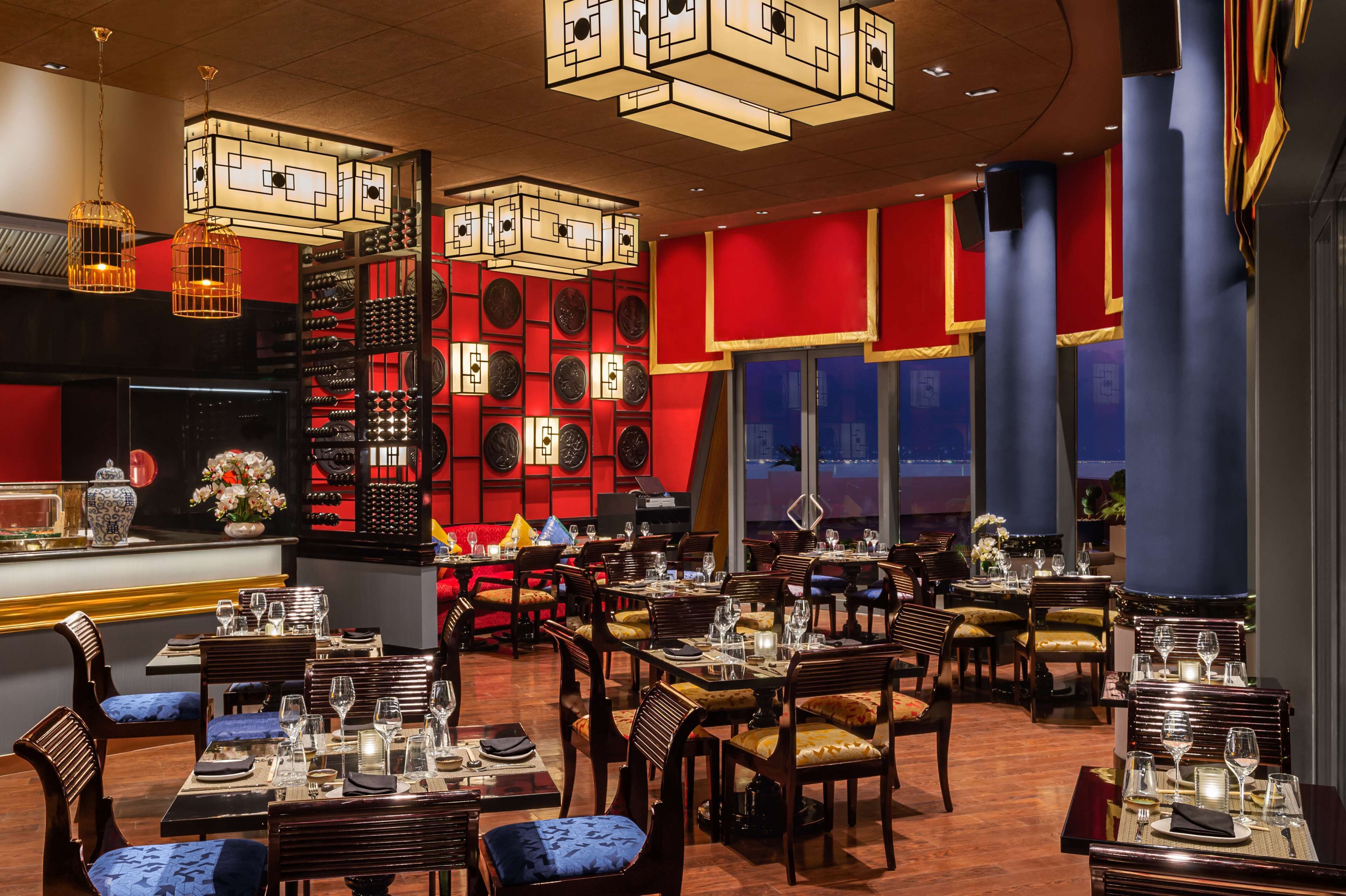 Un restaurant doté de plusieurs tables, de chaises et d’un mur décoratif orné de motifs circulaires.