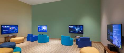A modern room with multiple screens displaying content, comfortable seating, and a wooden floor.