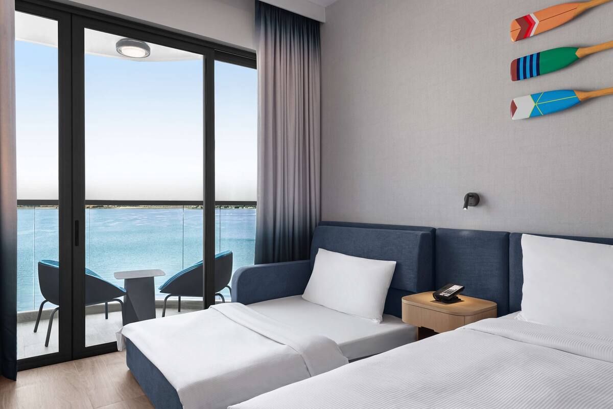 Ein Hotelzimmer mit Balkon, einem Bett, einem kleinen Tisch und einem Stuhl.