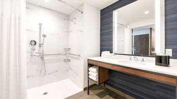 A modern bathroom with a glass-enclosed shower, a large mirror, and a wooden vanity.