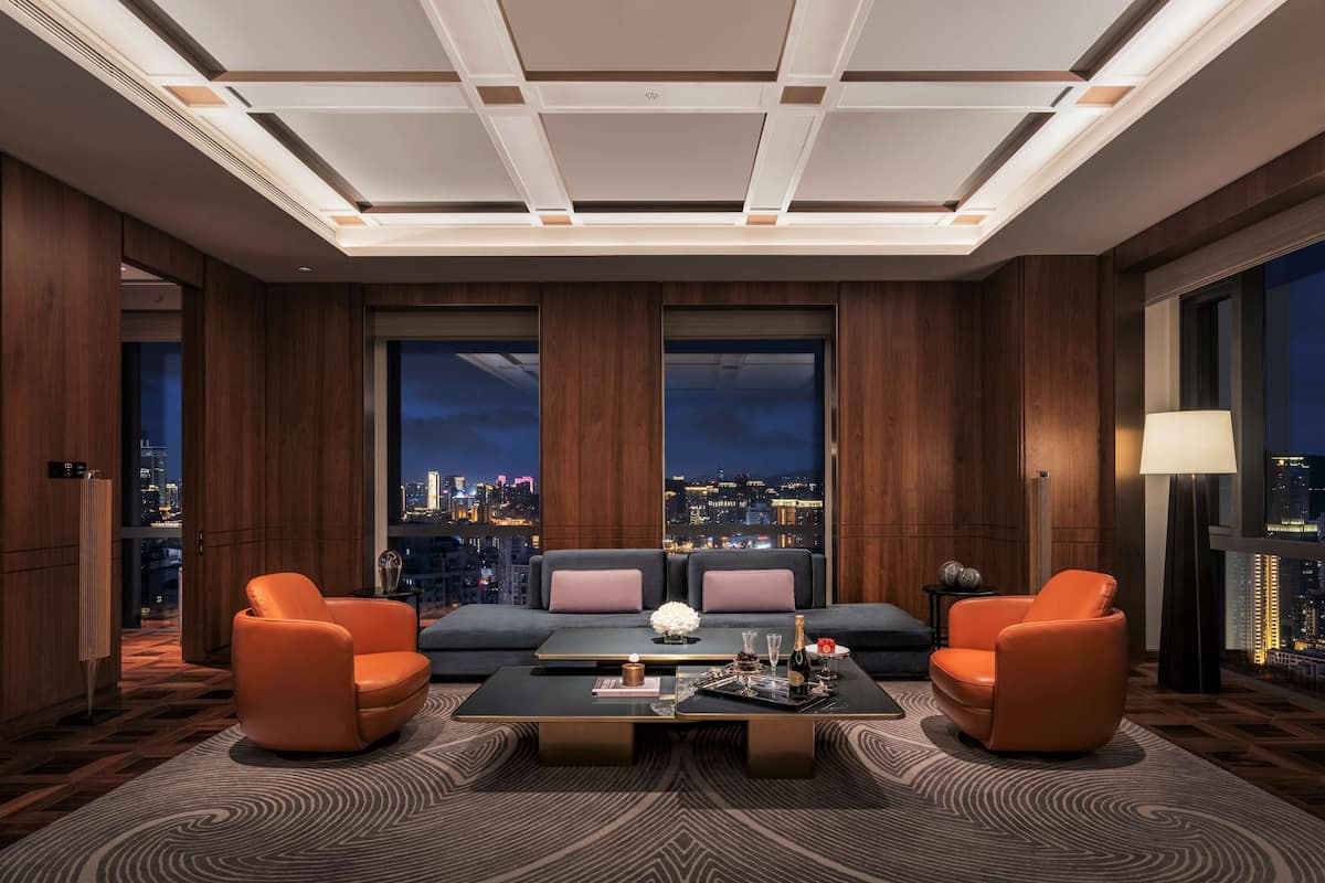 Ein modernes Wohnzimmer mit Stadtblick, einer Sofagarnitur, einem Couchtisch und zwei Sesseln.