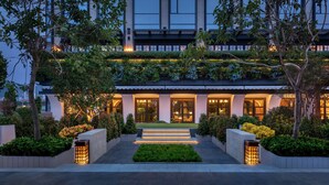 Un hôtel moderne doté d’une entrée bien éclairée, d’un jardin aménagé et d’un bâtiment à plusieurs étages avec de grandes fenêtres.