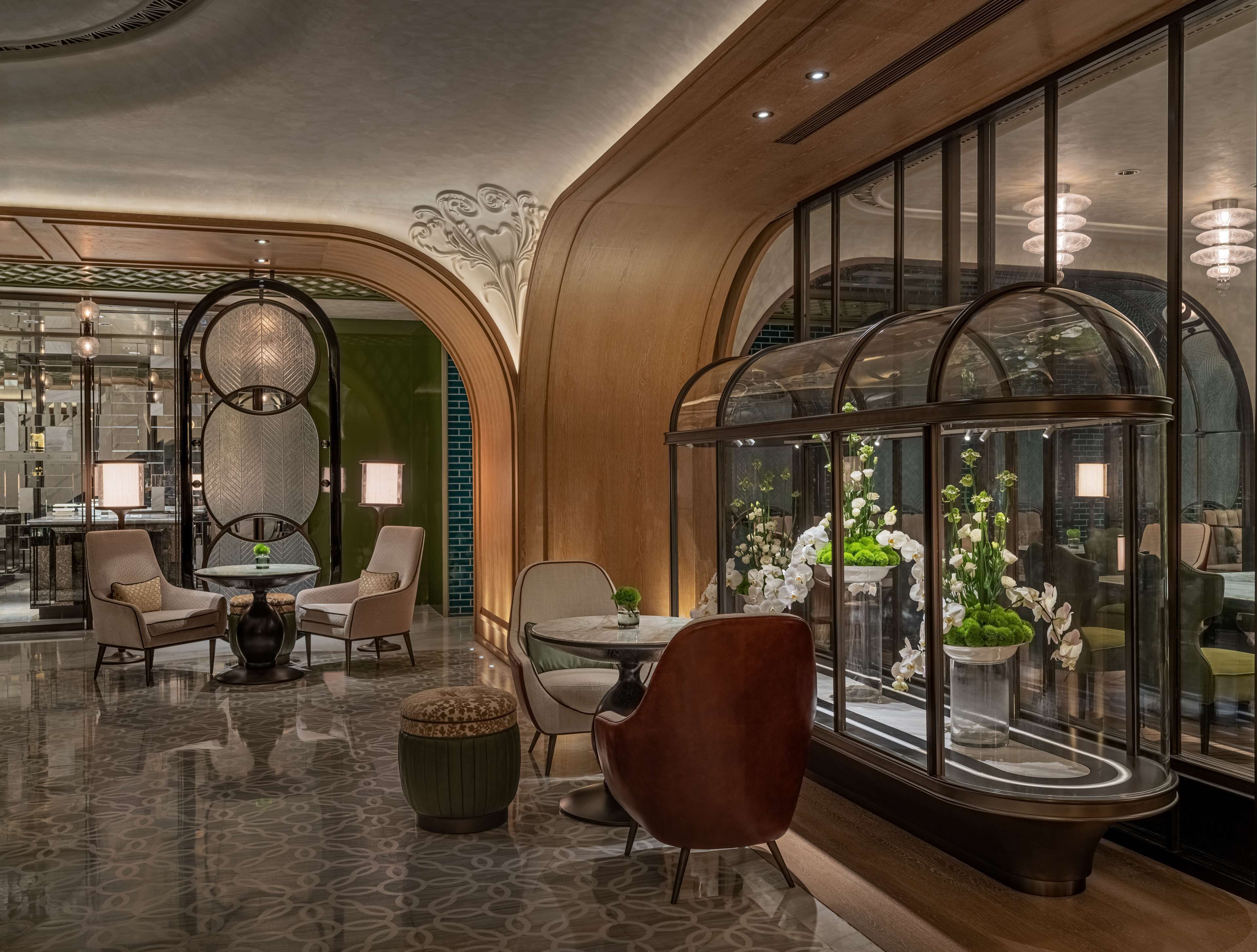 A luxurious lobby with a polished floor, elegant seating, and large windows with decorative glass panels.
