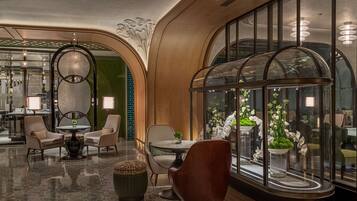 A luxurious lobby with a polished floor, elegant seating, and large windows with decorative glass panels.