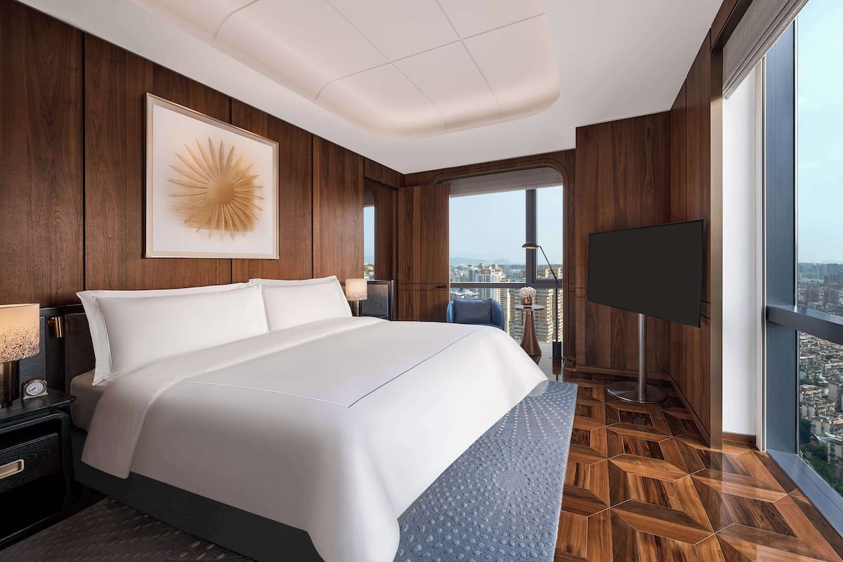 Ein modernes Hotelzimmer mit einem großen Bett, einem Flachbildfernseher und Blick auf die Stadt.