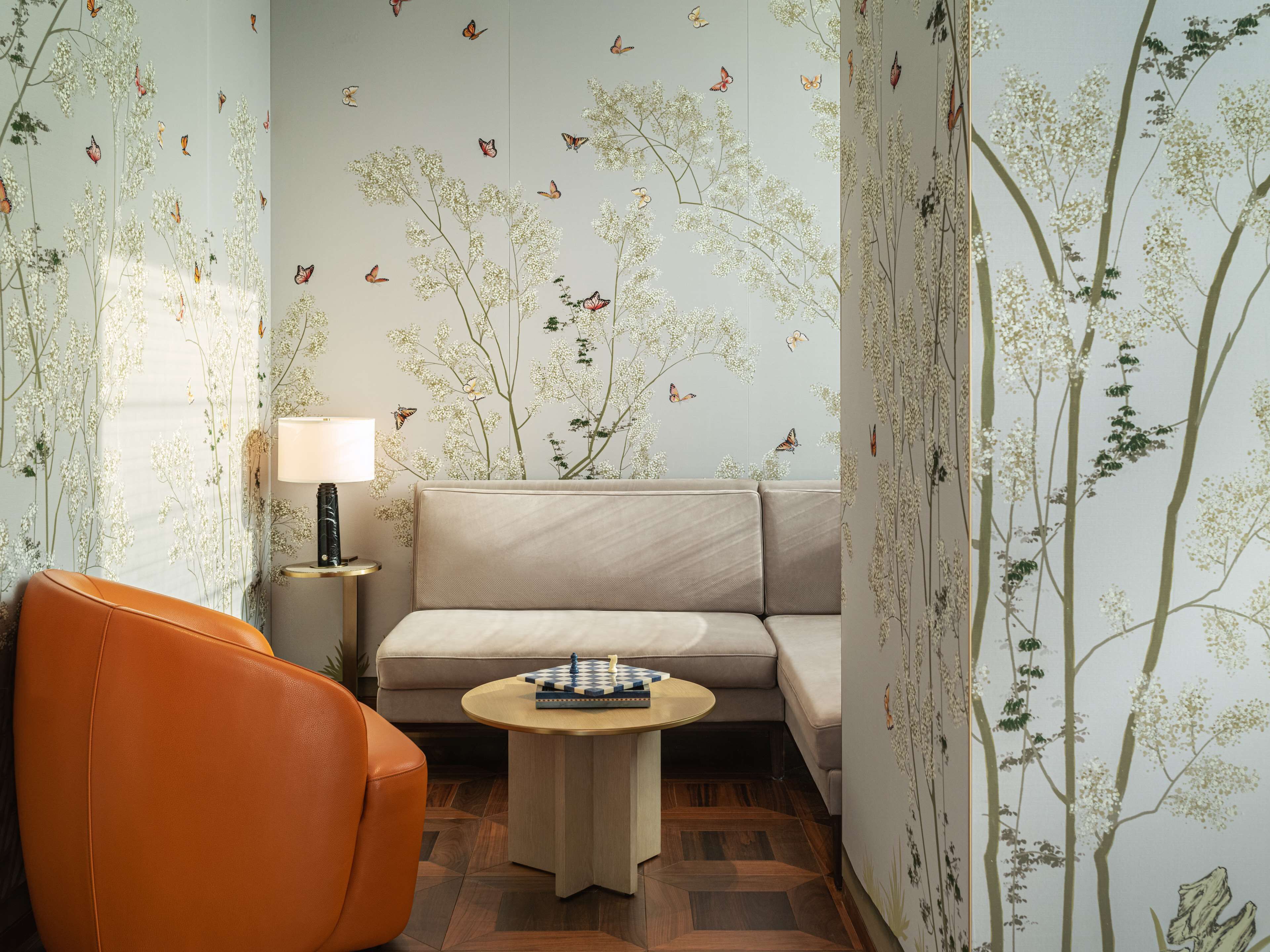 Ein Zimmer mit einer Couch, einem Sessel, einer Lampe und einem Tisch mit Schachbrett.