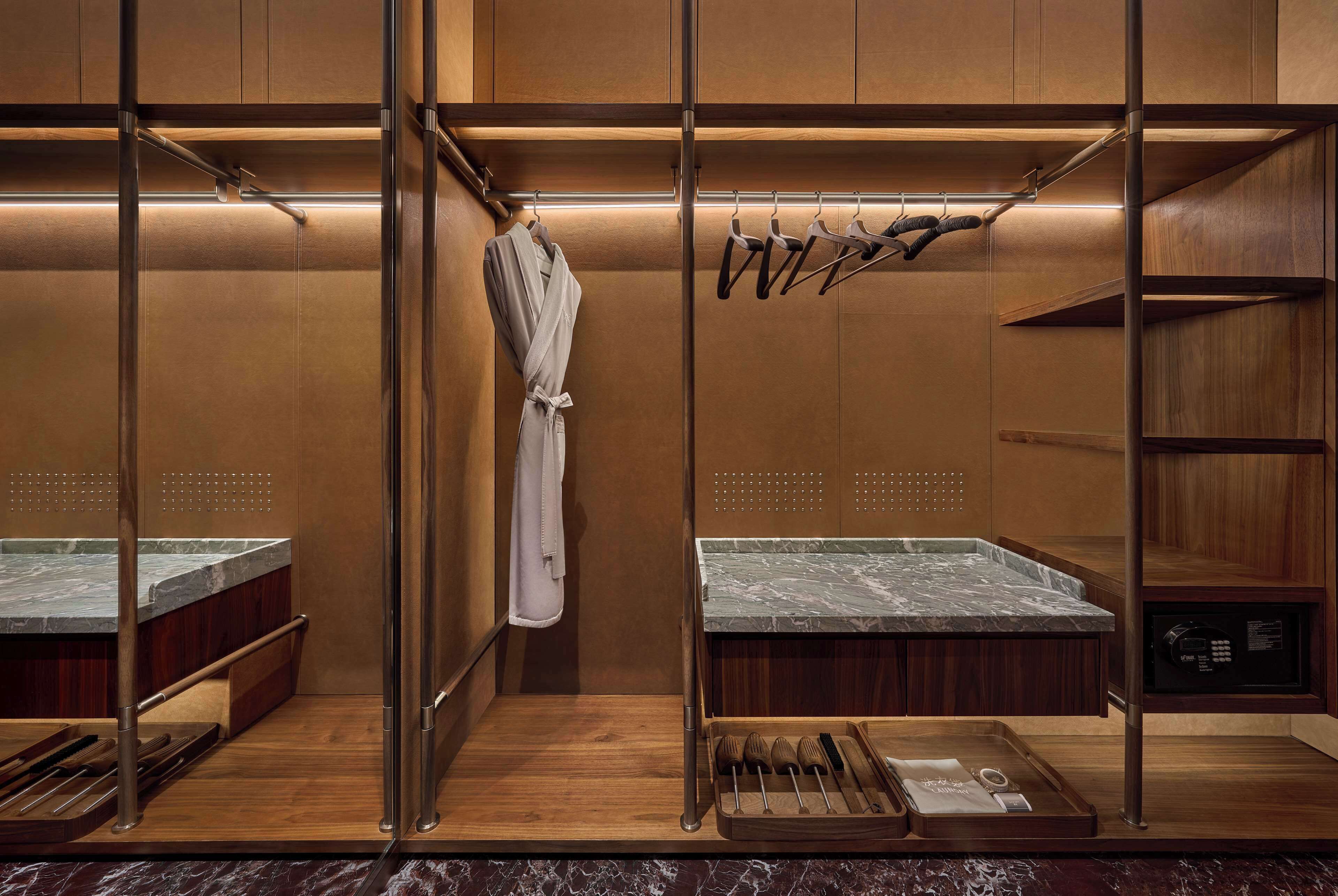 A modern bathroom with a wooden vanity, a robe hanging on a rack, and a set of toiletries on the counter.