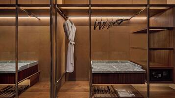 A modern bathroom with a wooden vanity, a robe hanging on a rack, and a set of toiletries on the counter.