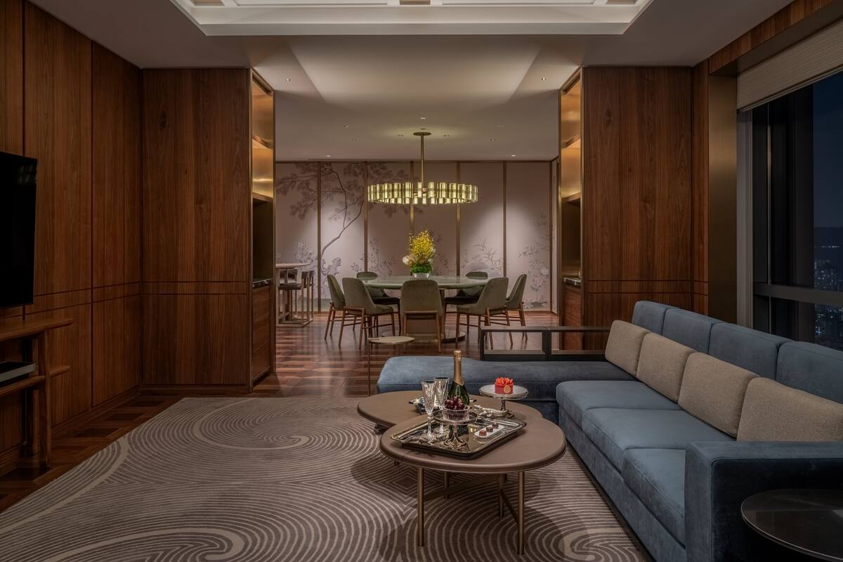 Ein modernes Wohnzimmer mit einem blauen Sofa, einem Couchtisch und einem Essbereich mit einer Chandelüster.