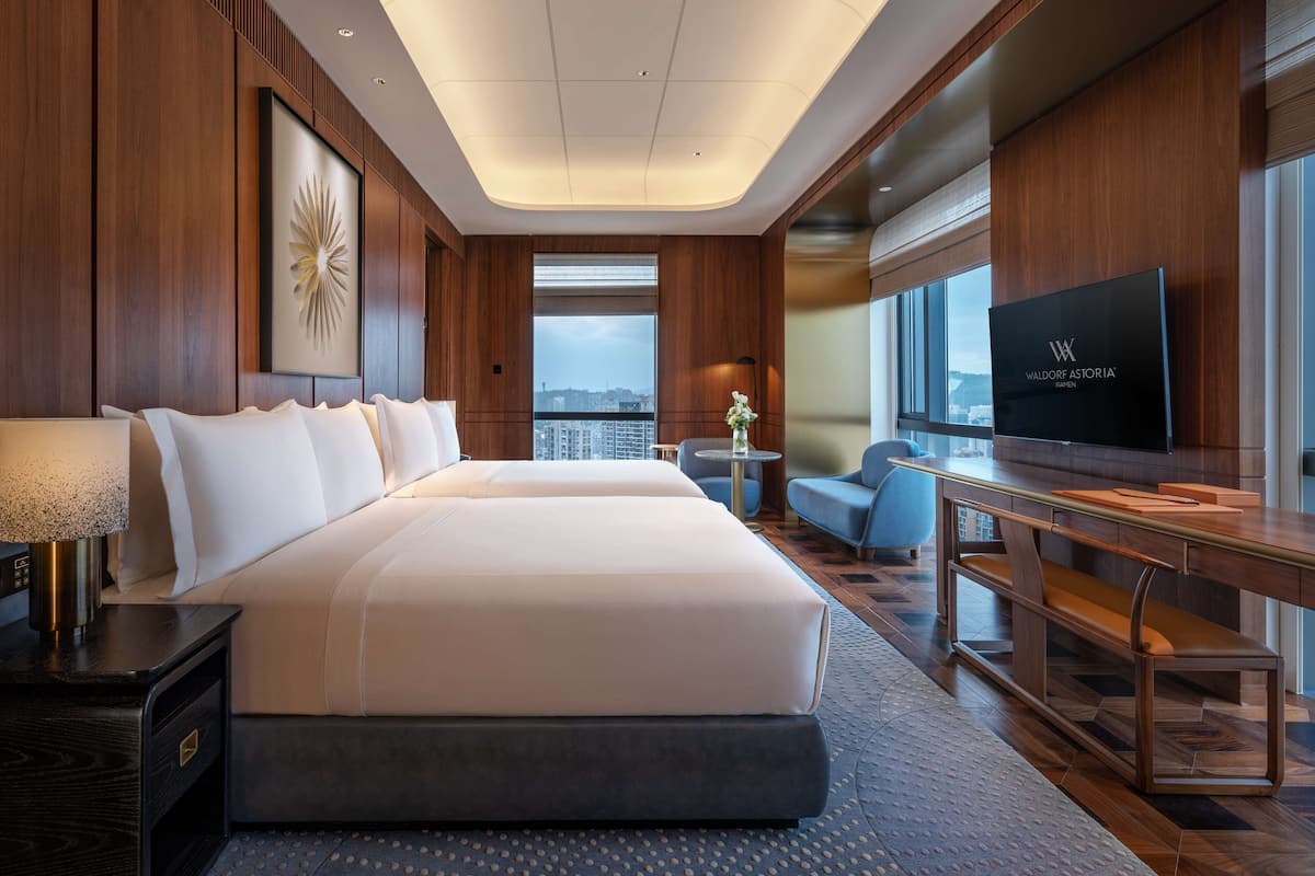 Ein modernes Hotelzimmer mit einem großen Bett, einem Schreibtisch, einem Fernseher und Blick auf die Stadt.