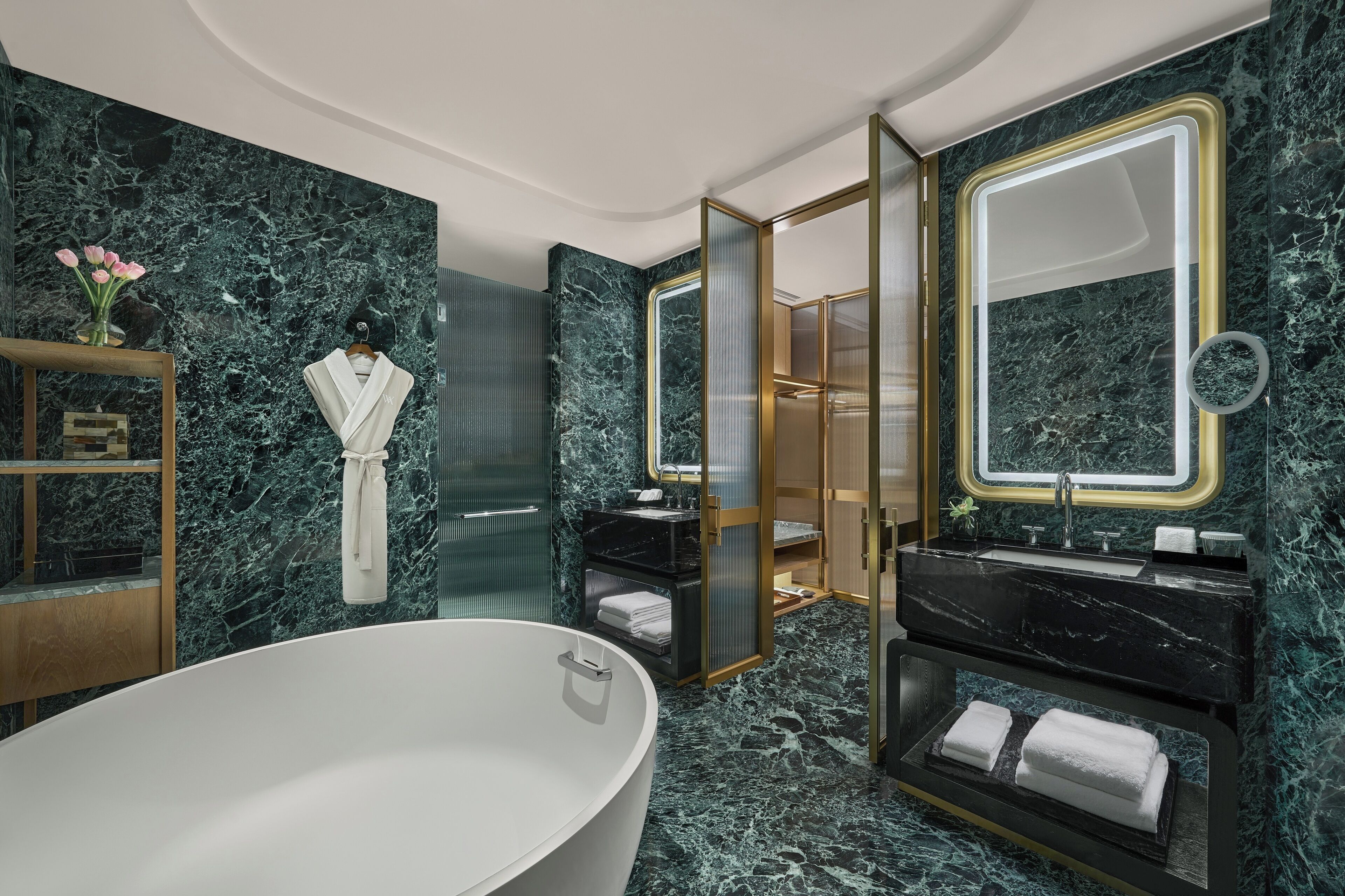 A modern bathroom with a freestanding bathtub, marble walls, and a vanity with a mirror.