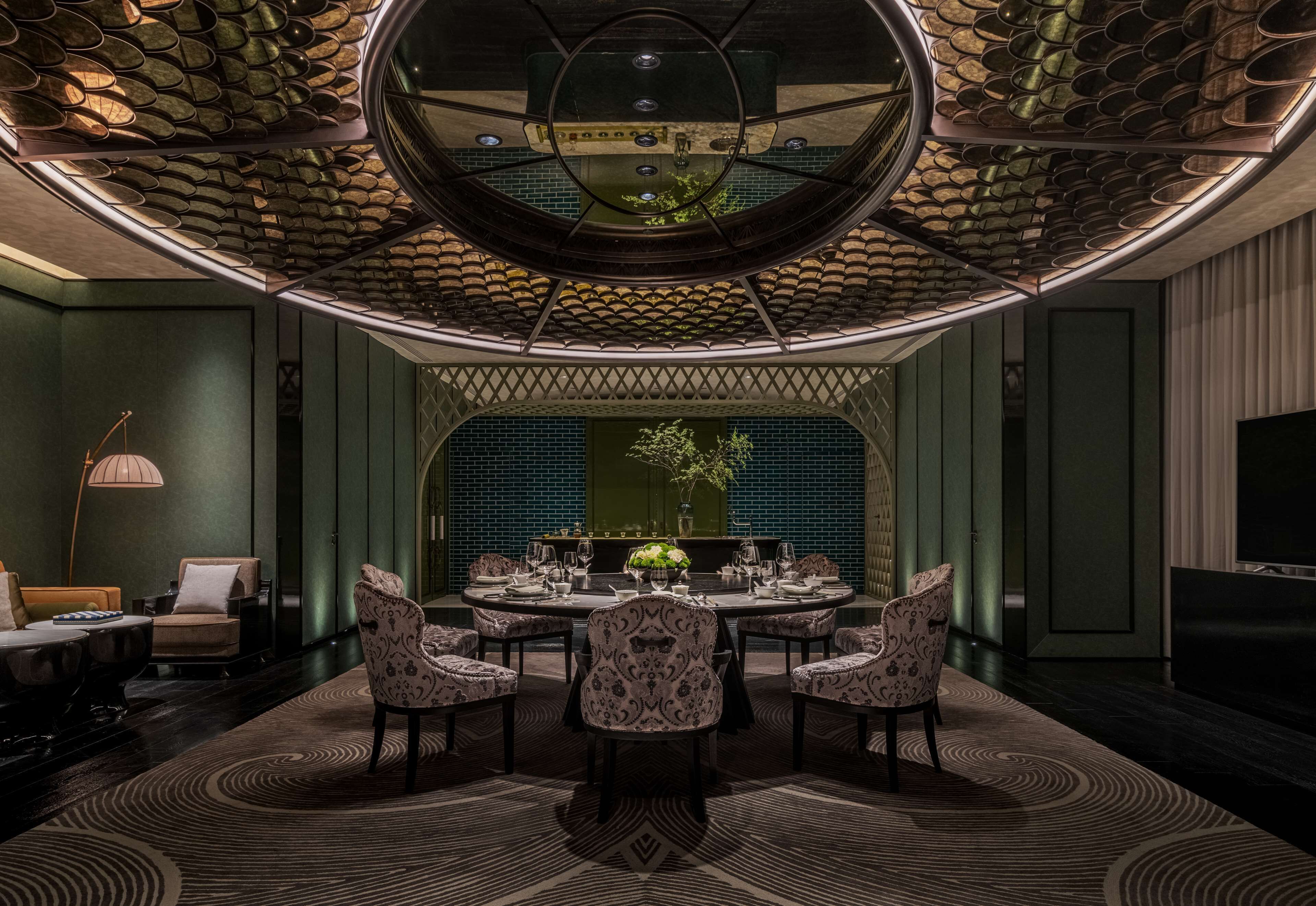 Un espace repas avec une table ronde, des chaises à motifs et un plafond décoratif.