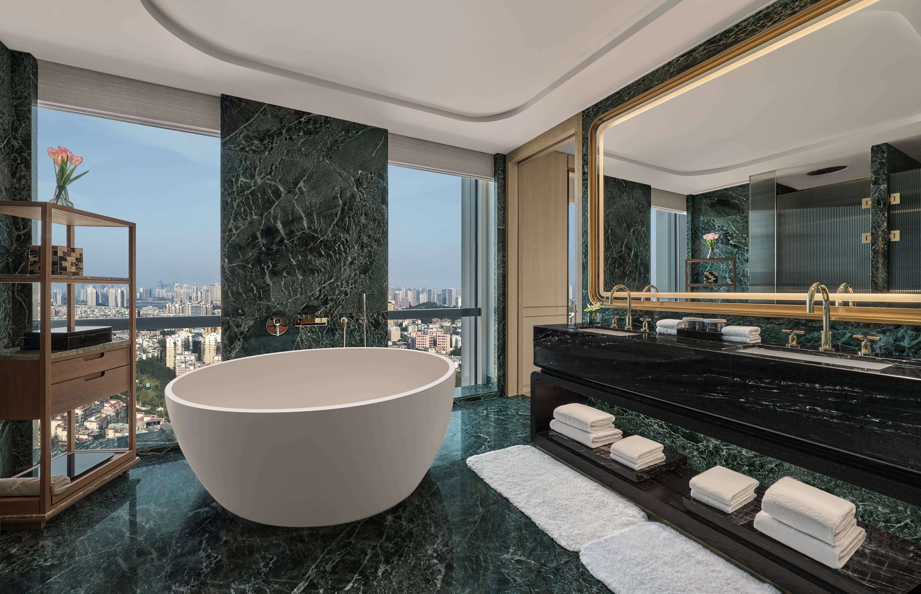 A modern bathroom with a large freestanding bathtub, a black vanity with dual sinks, and a large mirror.