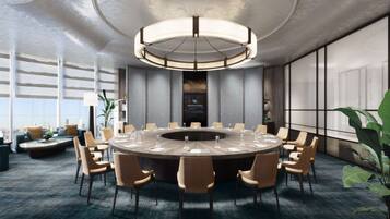 A modern conference room with a round table, chairs, and a large chandelier.
