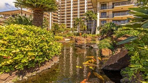 Un hôtel doté d’un bassin à carpes koï, entouré d’une végétation luxuriante et de palmiers.