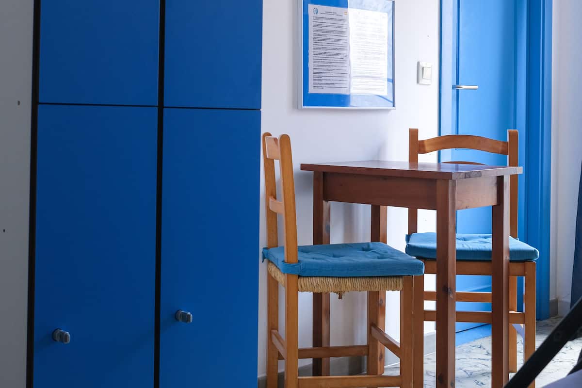 Una habitación con armarios azules, una mesa de madera con cojines azules, y una puerta azul.