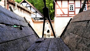 A narrow wooden pathway leading to a traditional building with a steep roof and exposed wooden beams.