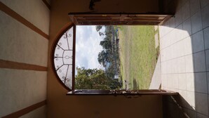 A room with a large arched window, a tiled floor, and a door with a metal handle.