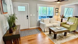 A living room with a white sofa, a green armchair, a wooden coffee table, and a ceiling fan. - The Perfect Relaxing Oasis for your family’s Island Getaway (Isle of Palms)