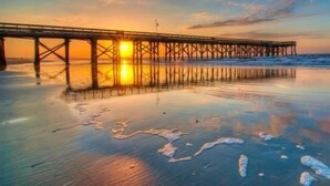 A pier extending into calm waters at sunset. - The Perfect Relaxing Oasis for your family’s Island Getaway (Isle of Palms)