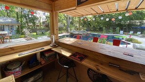 A wooden interior with a wooden table and chairs, a sign reading "SunTrust Park 2017", and a view of an outdoor swimming pool area. - The Perfect Relaxing Oasis for your family’s Island Getaway (Isle of Palms)